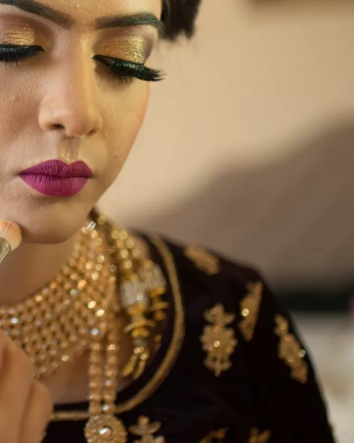 Maquillage et bijoux dorés, application de rouge à lèvres